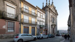 Een straat met keien, geflankeerd door historische gebouwen, met een opvallende kerk en een klokkentoren.