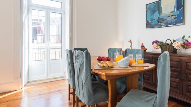 Een eetruimte met een houten tafel, stoelen en uitzicht door een glazen deur.