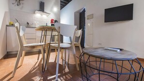 Cocina compacta con comedor, una mesa redonda y un televisor de pantalla plana montado en la pared.