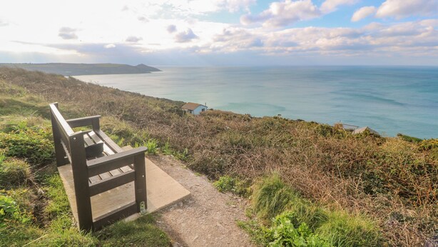 A wooden bench overlooking a coastal view with a clear sky and distant land. - Lodge 23 (Torpoint)