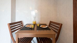 A wooden dining table with two chairs, a glass bottle of orange juice, two plates with croissants, and a glass of coffee.