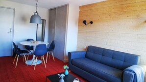 A modern living room with a blue sofa, a round dining table with chairs, a small coffee table, and a red carpet. - NEW - ULTRA CENTER & PANORAMIC VIEW (Huez)