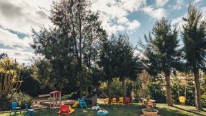 A backyard with a play area, including a slide and swings, surrounded by trees and a clear sky. - Vale Pisco - Villa Master (Carvalhal Bombarral)