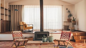 A cozy living room with a fireplace, comfortable seating, and a large window with curtains. - Vale Pisco - Villa Master (Carvalhal Bombarral)
