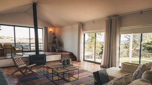 A spacious living room with a large window, a fireplace, and a colorful rug. - Vale Pisco - Villa Master (Carvalhal Bombarral)