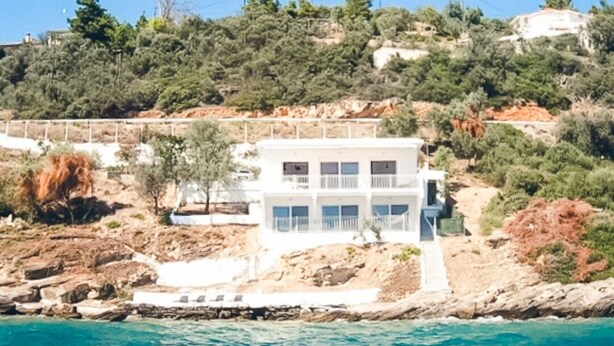 A white building with multiple balconies overlooking a coastal area with clear blue water. - Villa facing the sea, feet in the water (Chrisi Akti Panagias)
