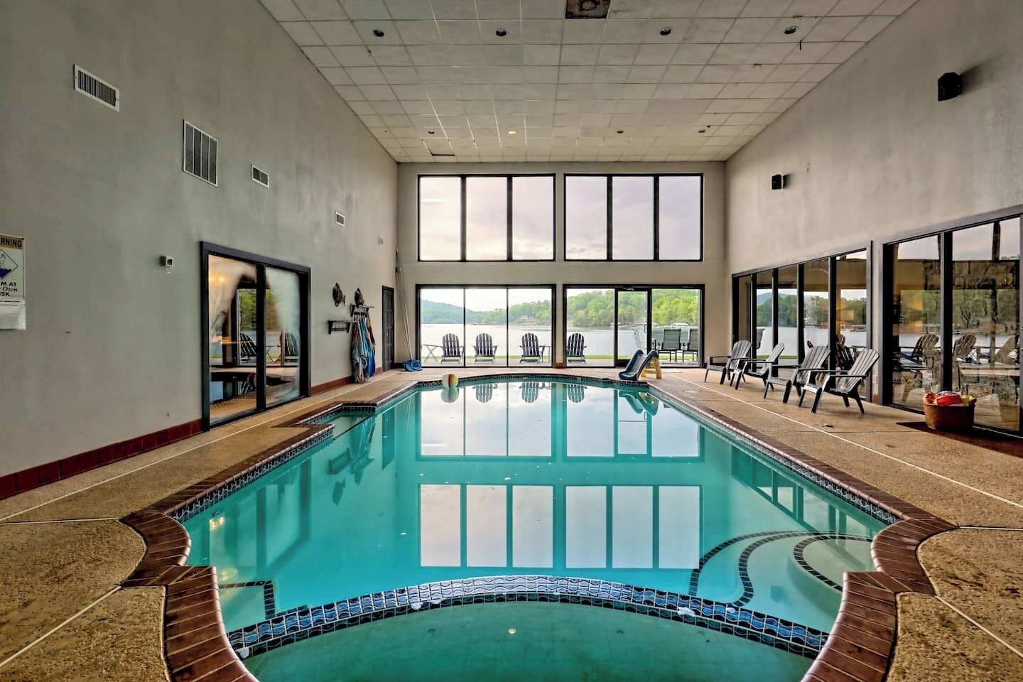 Ein Innenpool mit freiem Blick ins Freie, umgeben von Liegestühlen und einem großen Fenster.