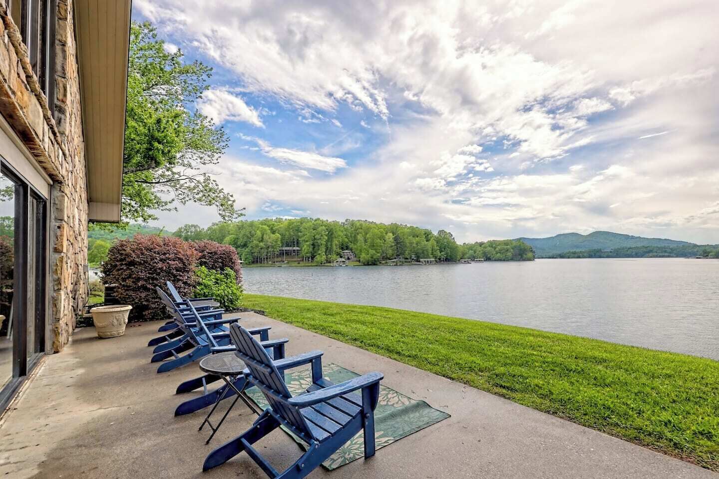 A lakeside patio with outdoor seating and a view of the lake and surrounding greenery.