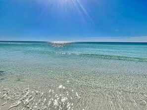 Ein Strand mit klarem, flachem Wasser und strahlender Sonne.
