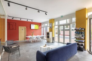 Un interno moderno con un divano blu, un'area pranzo con sedie bianche e una macchina distributrice.