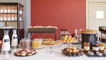 A buffet table with various food items including pastries, donuts, and jars of spreads.