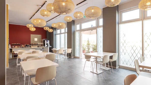 A modern dining area with multiple tables and chairs, large windows, and decorative woven light fixtures. - B&B Hotel Roma Fiumicino Aeroporto Fiera 2 (Fiumicino)
