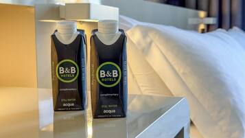 Two B&B Hotels branded still water acqua juice cartons on a hotel room table.