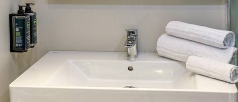 A bathroom sink with a mirror above it, a towel rack with towels, and two bottles of hand soap.