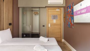 Une chambre d’hôtel avec un lit, une porte en bois, un miroir et un panneau fixé au mur.