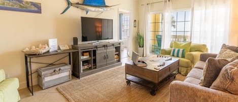 Uma sala de estar com televisão, mesa de centro, sofá e mesa de jantar.