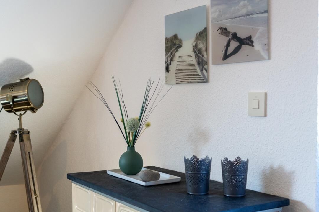 A room with a desk, a lamp, a vase with plants, and two decorative vases.