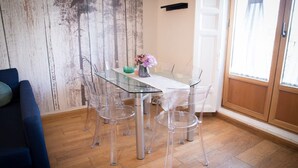 Un coin repas avec une table en verre et des chaises transparentes, un vase rempli de fleurs et un plancher en bois.