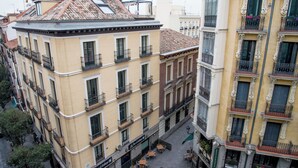 Un immeuble à plusieurs étages doté de balcons, d’une terrasse et d’une enseigne indiquant la présence d’un bar.