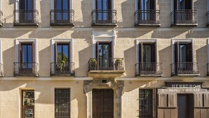 Un edificio de varios pisos con entrada central, balcones y un letrero que indica un negocio.