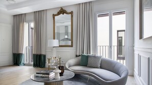 Un salón moderno con un sofá gris curvo, una mesa de centro redonda y un espejo grande.