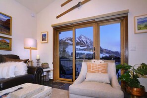 A living room with a sofa, armchair, and a table with a lamp. - Crested Mtn. North J6 (Mt. Crested Butte)