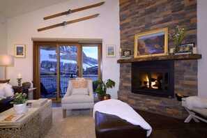 Una sala de estar con chimenea, un ventanal con vistas y una pared de piedra.