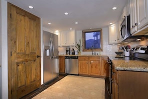A kitchen with wooden cabinets, stainless steel appliances, and a view of a building through a window.