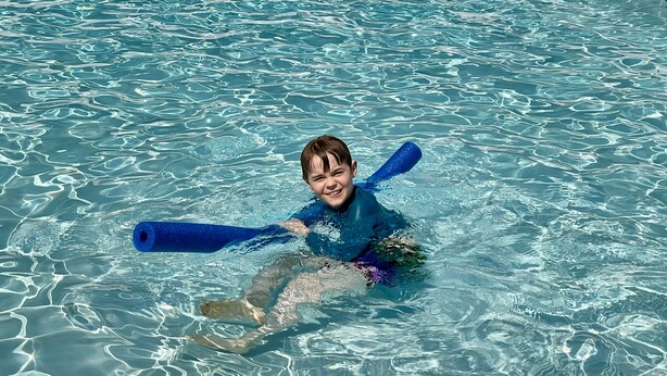 Un enfant dans une piscine, équipé de bouées bleues.