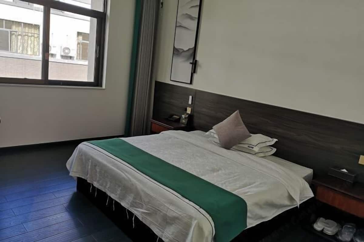 Et hotelværelse med en seng, et natbord, et spejl og et vindue.