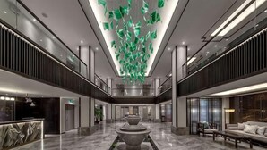 A spacious lobby with a central fountain, a reception desk, and a seating area. - Longling Hotel (Longling)