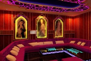 Ein Zimmer mit einer gebogenen Sitzecke, Wandkunst und einem tischartigen Möbelstück mit Neonbeleuchtung.