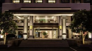 A modern hotel entrance with a double staircase, large windows, and a central potted plant. - Longling Hotel (Longling)