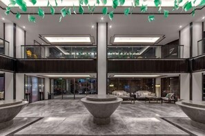 A spacious lobby with a central seating area, a staircase, and a glass railing.