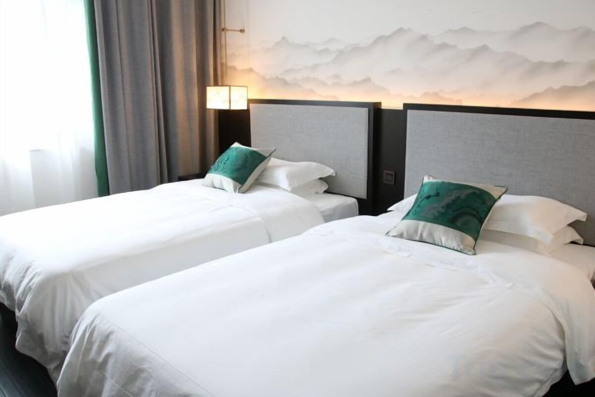 Two single beds with headboards, a nightstand, and a wall-mounted lamp.
