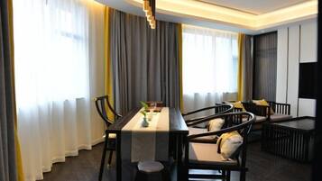 A modern dining area with a long table, chairs, and a TV on the wall.