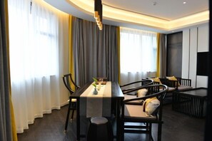 A modern dining area with a long table, chairs, and a TV on the wall. - Longling Hotel (Baoshan)