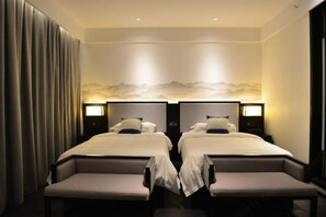Habitación de hotel con dos camas, un ventanal grande y un mural de montañas en la pared.