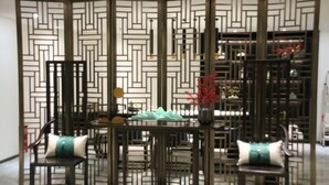 A room with a traditional Asian-style partition, a dining table with chairs, and a decorative vase with red flowers. - Longling Hotel (Longling)