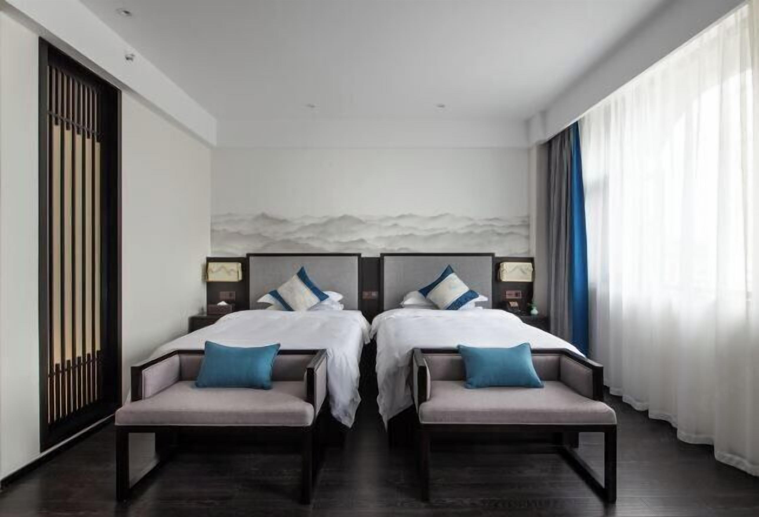 Une chambre d’hôtel avec deux lits, un canapé, une table de chevet et une vue sur la mer.