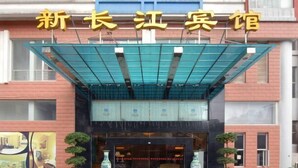 A hotel entrance with a covered entrance, large windows, and potted plants.