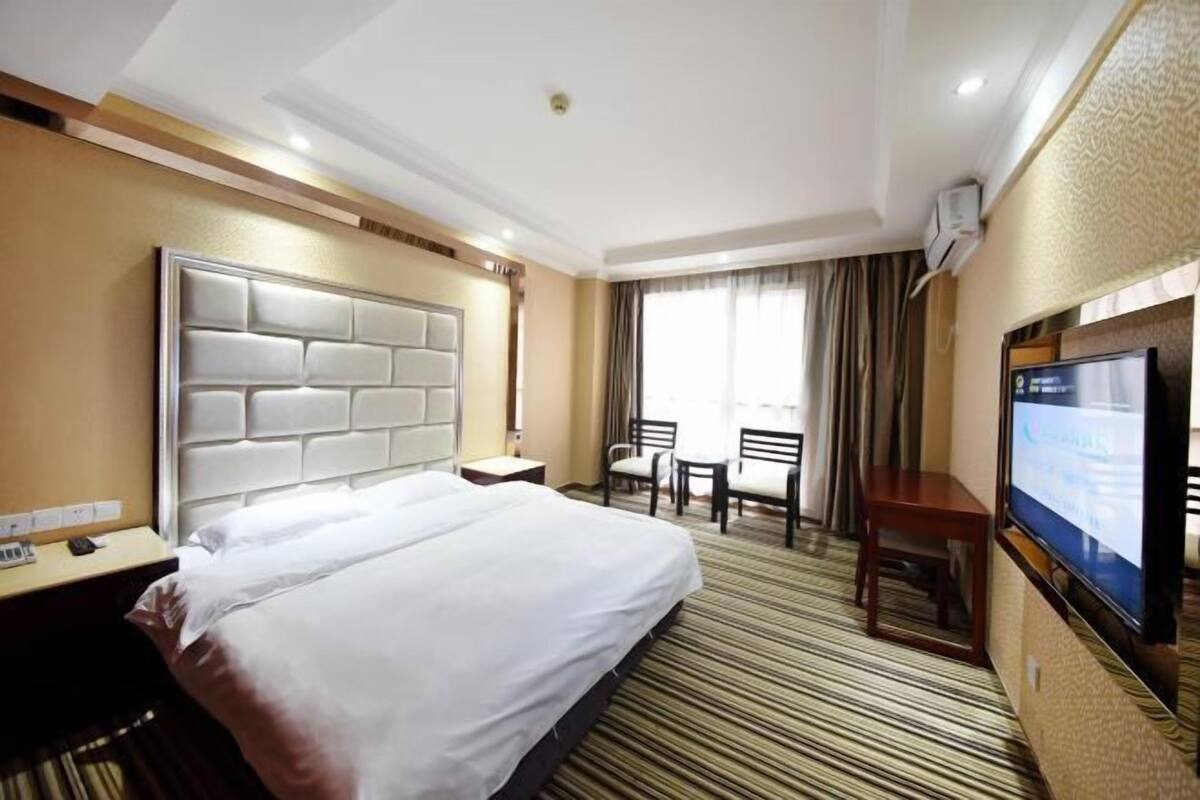 Quarto de hotel com uma cama grande, televisão, escrivaninha e uma cadeira.