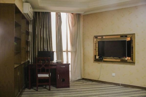 A hotel room with a desk, chair, air conditioning unit, and a television mounted on the wall. - Xinchangjiang Hotel (Changsha)