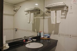 A bathroom with a black countertop, a white sink, and a mirror. There are towels hanging on a rack and a trash bin on the counter. - Xinchangjiang Hotel (Changsha)
