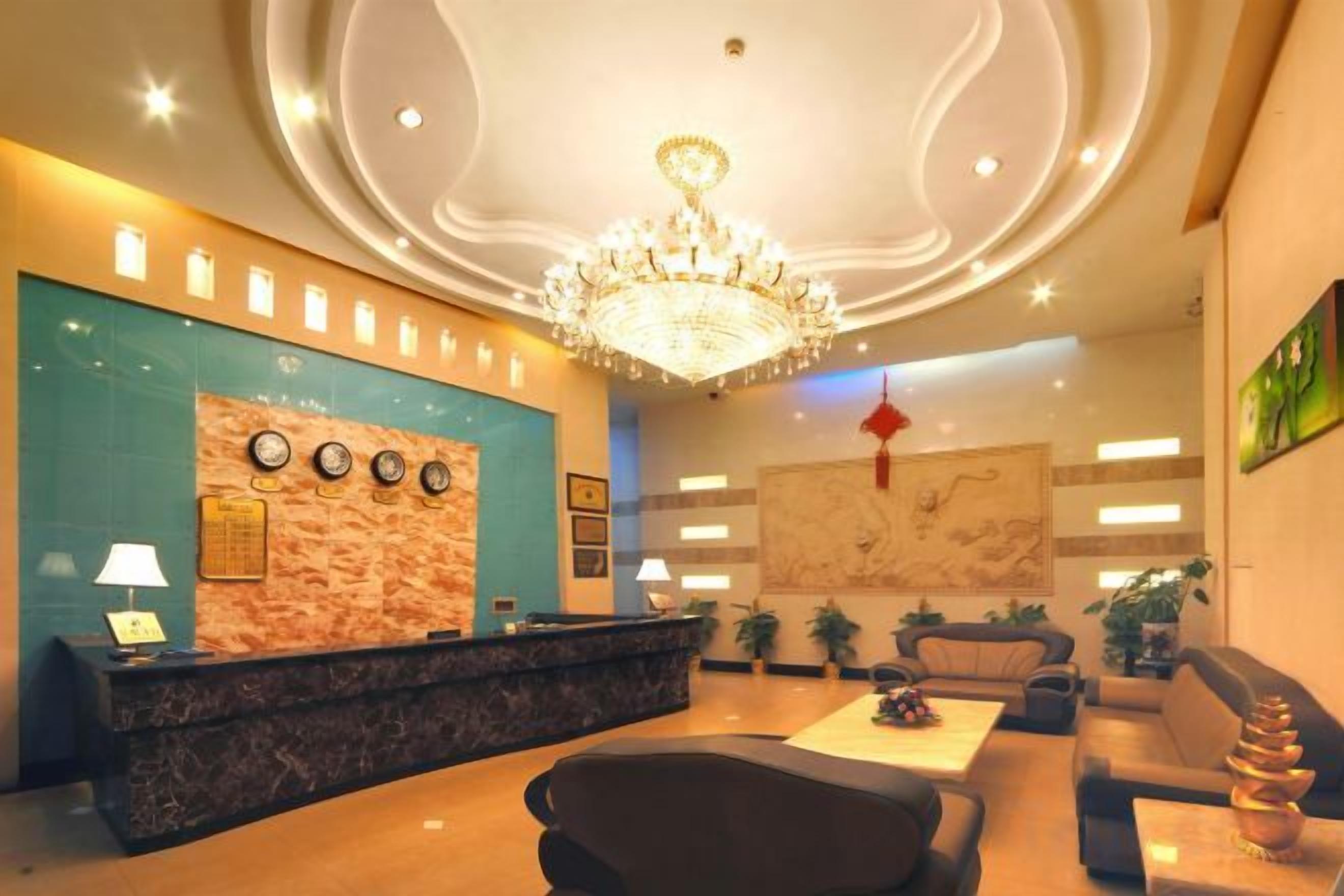 A hotel lobby with a reception desk, seating area, and a chandelier.