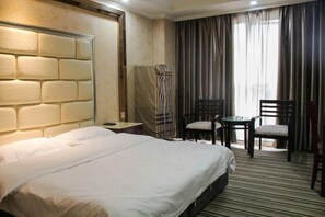 A hotel room with a large bed, a headboard with a textured design, a small table with two chairs, and a view of the outdoors through curtains. - Xinchangjiang Hotel (Changsha)