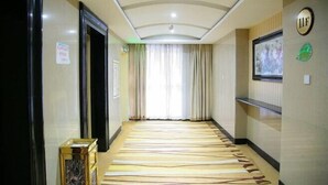 A hotel hallway with a patterned carpet, a reception desk, and a sign indicating room availability.