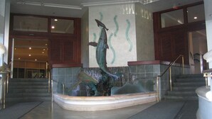 A lobby with a central fountain sculpture, a staircase, and a large window. - Resort Style with Hula Show, Fireworks and even Tiki Torches! (Honolulu)