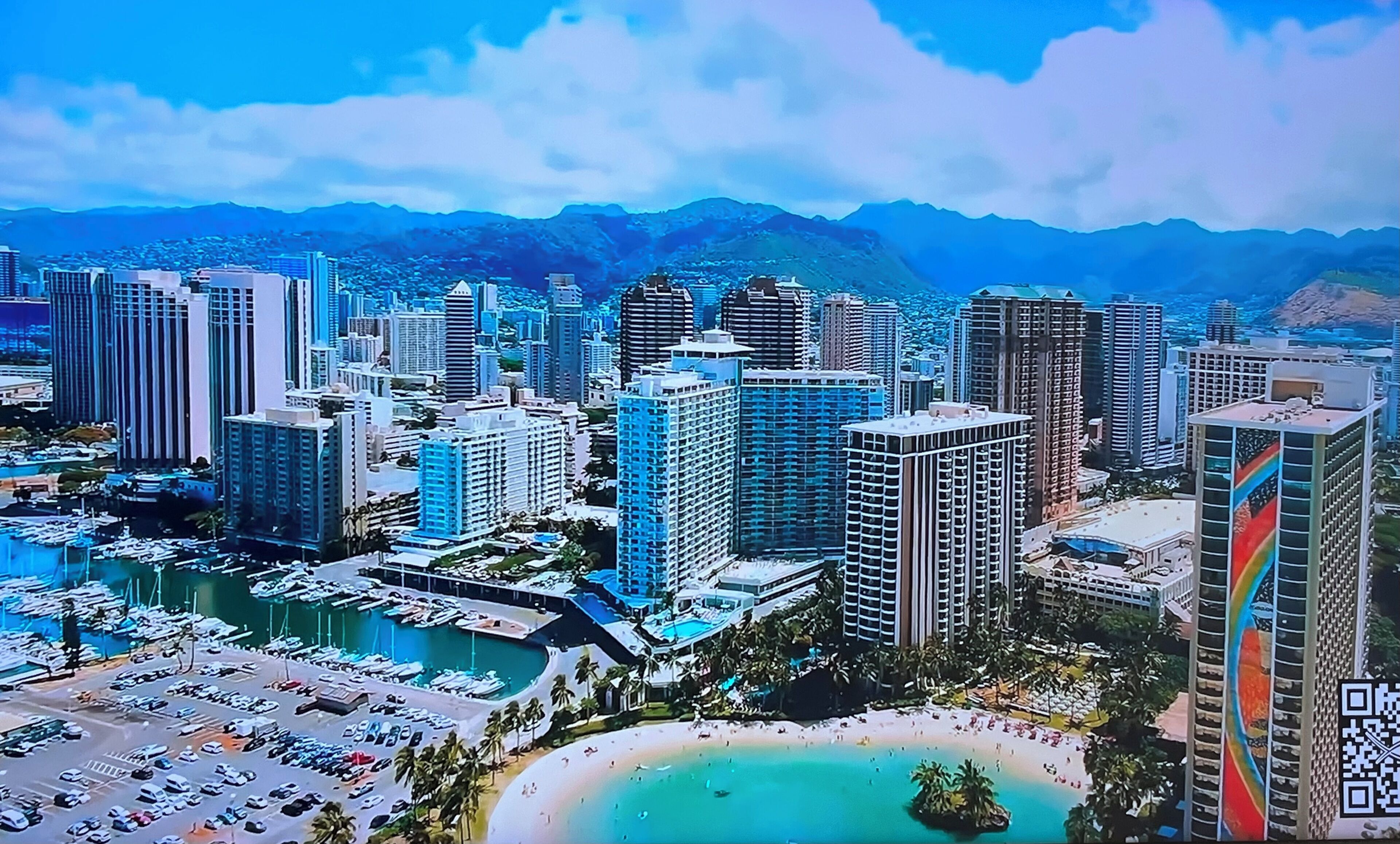 A coastal cityscape with high-rise buildings, a marina, and a beach.