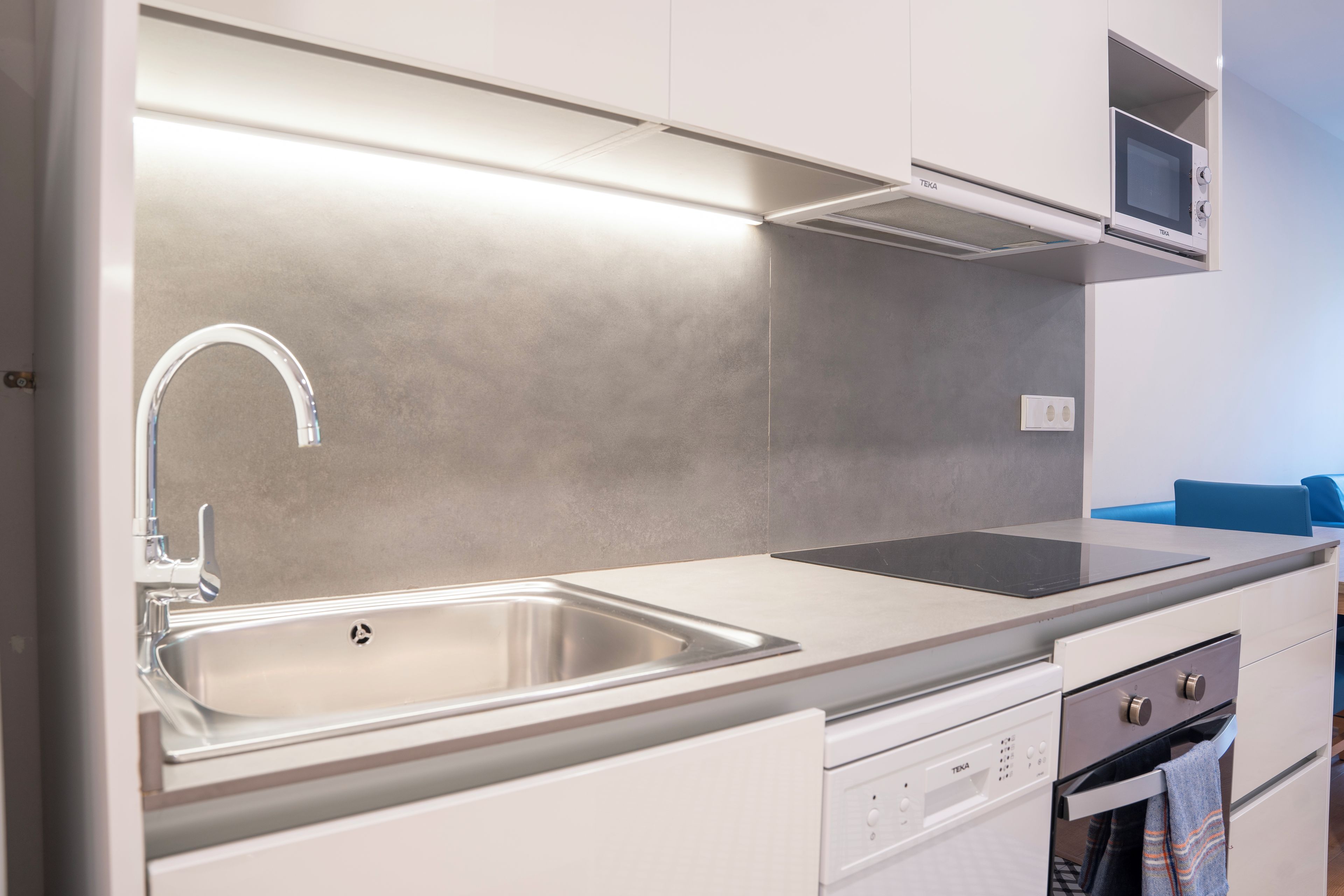 A modern kitchen with a stainless steel sink, a microwave, and a built-in oven.